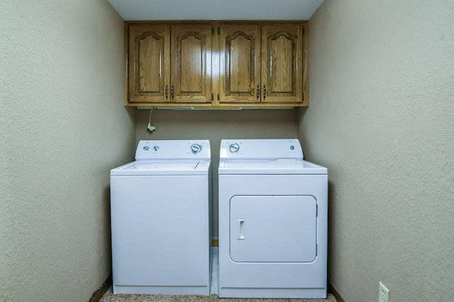 laundry room with separate washer and dryer and cabinets