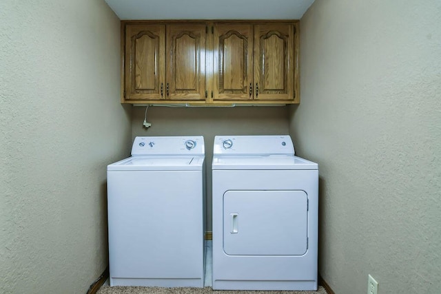 washroom with cabinet space, independent washer and dryer, and a textured wall