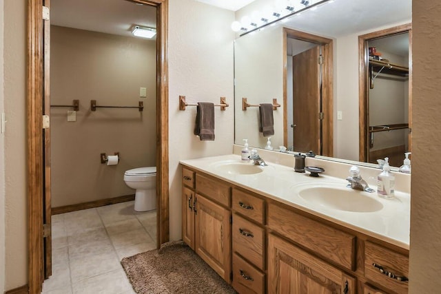 full bath featuring tile patterned floors, a sink, double vanity, and toilet