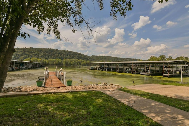 view of community with a dock, a forest view, and a water view