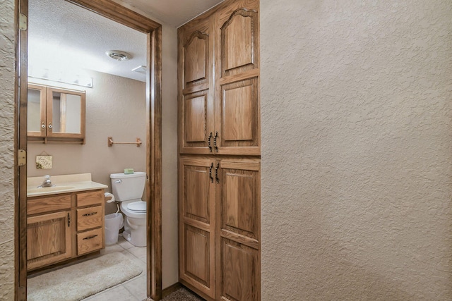 bathroom with tile patterned floors, vanity, toilet, and a textured ceiling