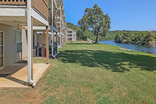 view of yard featuring ceiling fan, a patio, and a water view