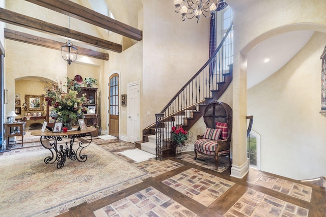 entryway featuring beamed ceiling, a notable chandelier, and a high ceiling