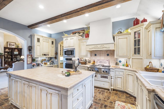 kitchen with appliances with stainless steel finishes, cream cabinets, decorative backsplash, and custom exhaust hood