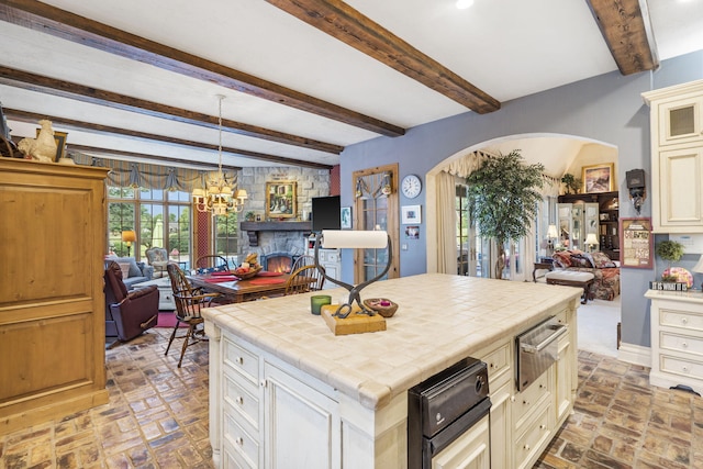 kitchen with beam ceiling, hanging light fixtures, a center island, and tile countertops