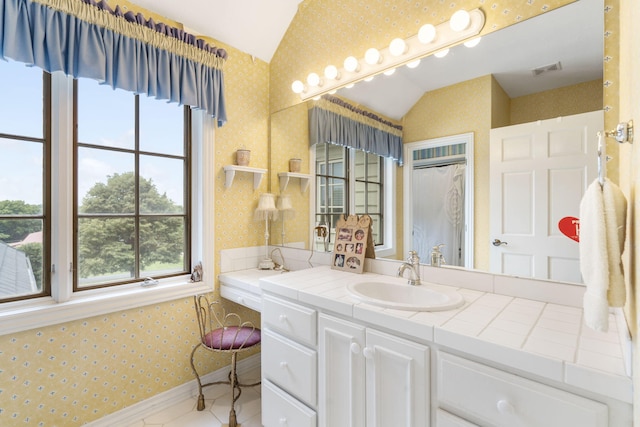 bathroom featuring plenty of natural light, vaulted ceiling, and vanity