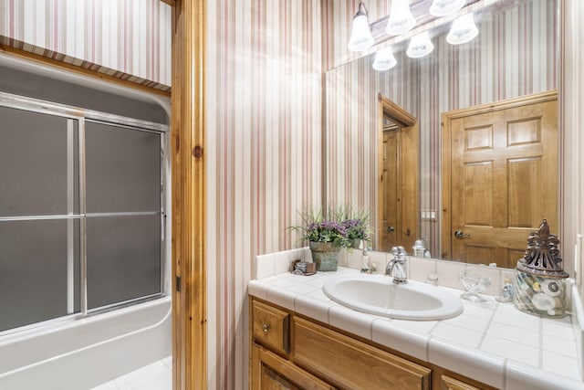 bathroom featuring combined bath / shower with glass door and vanity