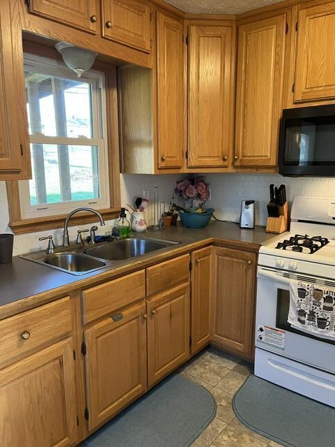 kitchen featuring light tile patterned flooring, sink, and white range with gas stovetop