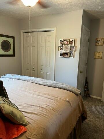 carpeted bedroom featuring ceiling fan, a textured ceiling, and a closet