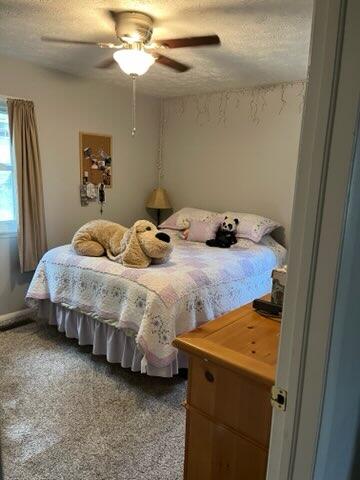 carpeted bedroom featuring a textured ceiling and ceiling fan