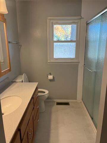 bathroom featuring a shower with shower door, vanity, and toilet