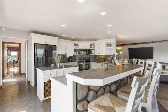 kitchen featuring stainless steel appliances, kitchen peninsula, white cabinetry, and a kitchen breakfast bar