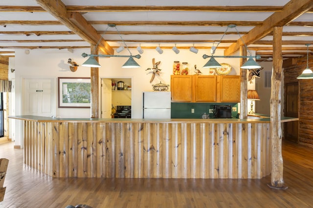 kitchen with pendant lighting, black range oven, hardwood / wood-style floors, and white fridge