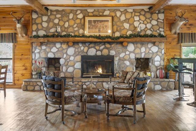 living room with a stone fireplace, beamed ceiling, and hardwood / wood-style flooring