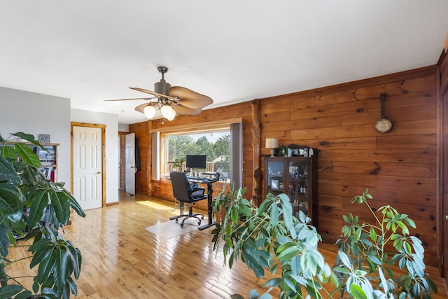 office space featuring ceiling fan, light hardwood / wood-style flooring, and wood walls