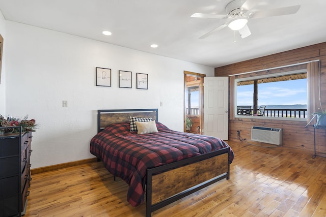 bedroom featuring ceiling fan, light hardwood / wood-style floors, and a wall mounted AC