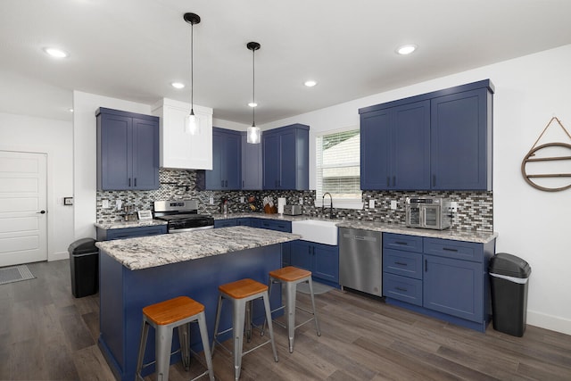 kitchen featuring sink, a center island, appliances with stainless steel finishes, dark hardwood / wood-style floors, and a breakfast bar