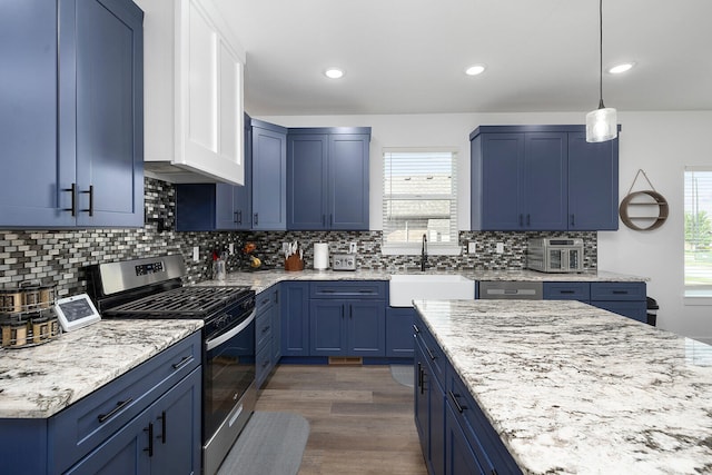 kitchen with stainless steel gas range oven, plenty of natural light, hanging light fixtures, and sink