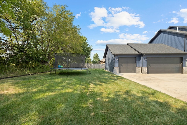 view of yard with a trampoline and a garage