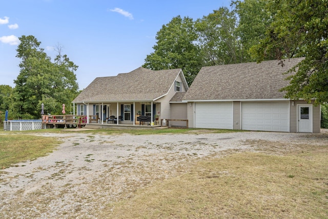 view of front of property featuring a front lawn, covered porch, and a garage