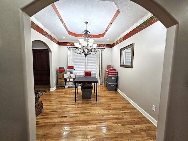 dining space with ornamental molding, hardwood / wood-style floors, an inviting chandelier, and a textured ceiling