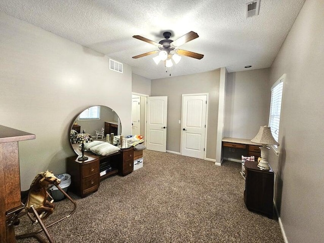 bedroom featuring ceiling fan, a textured ceiling, and dark carpet