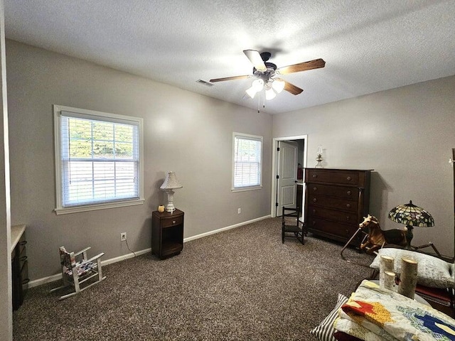 carpeted bedroom with a textured ceiling, multiple windows, and ceiling fan