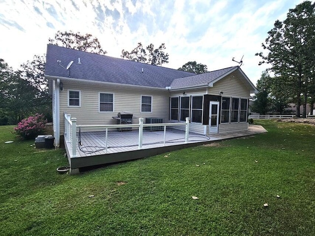 rear view of property featuring a sunroom, a deck, and a lawn