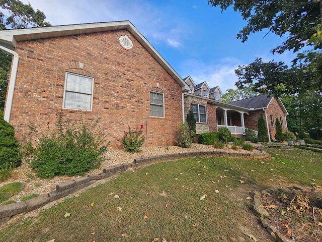 view of side of home with a porch and a lawn