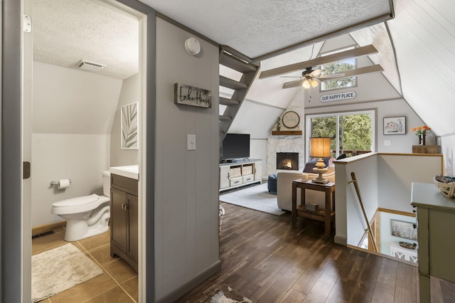 interior space featuring vaulted ceiling, toilet, hardwood / wood-style floors, and a textured ceiling