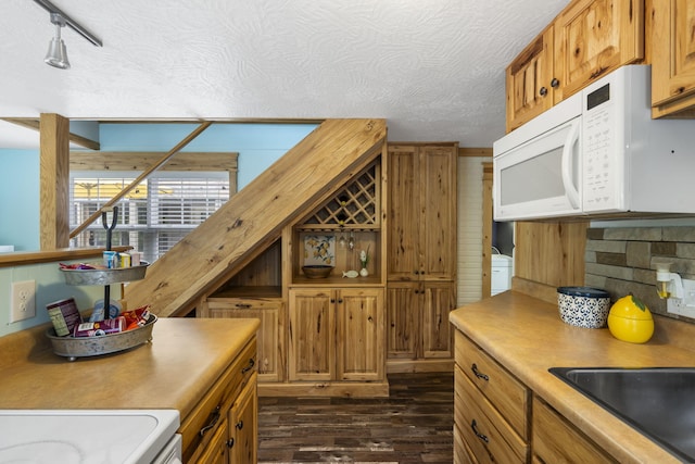 kitchen with stove, rail lighting, tasteful backsplash, dark hardwood / wood-style flooring, and a textured ceiling