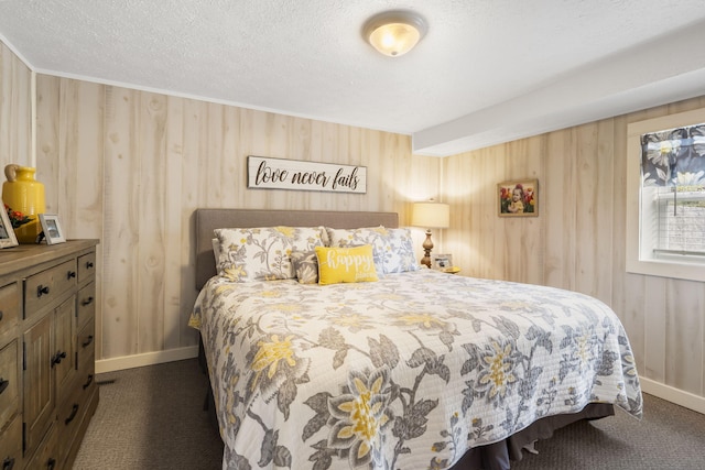 bedroom featuring a textured ceiling, wood walls, and dark colored carpet