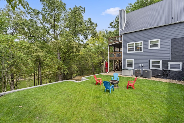 view of yard featuring a wooden deck, central air condition unit, and a fire pit