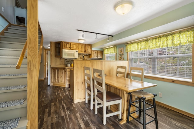 dining room featuring a textured ceiling, dark hardwood / wood-style flooring, and rail lighting