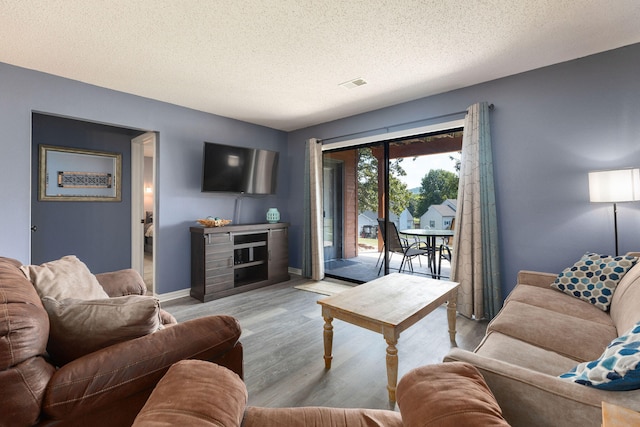 living room with light hardwood / wood-style floors and a textured ceiling