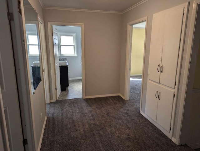 hall with dark colored carpet and crown molding