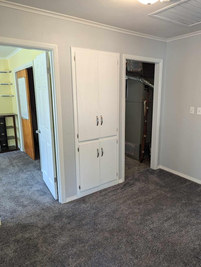 unfurnished bedroom featuring dark carpet, a closet, and crown molding