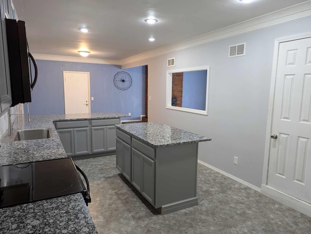 kitchen with range, a kitchen island, light stone countertops, crown molding, and gray cabinets