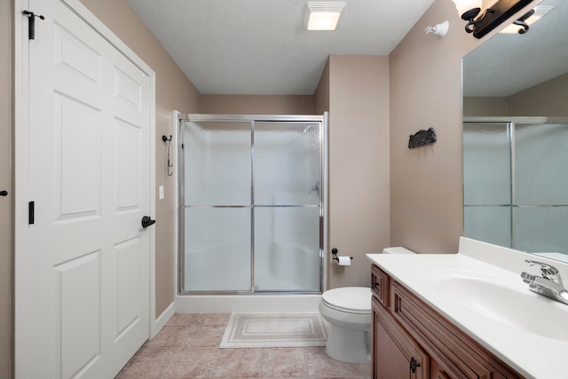 bathroom with an enclosed shower, vanity, tile patterned flooring, and toilet