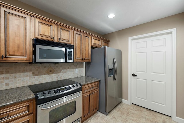 kitchen with dark stone countertops, light tile patterned floors, tasteful backsplash, and stainless steel appliances