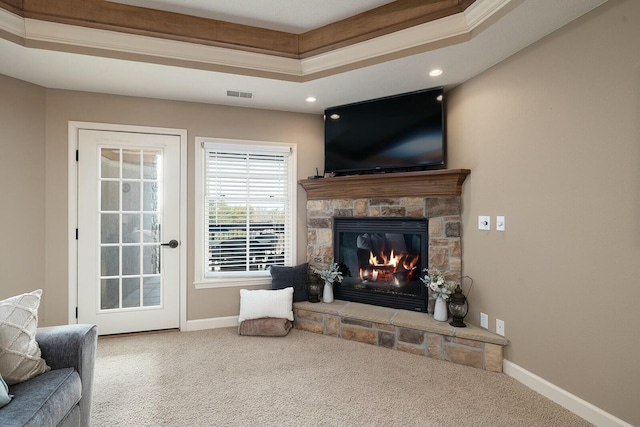 living room featuring carpet flooring, a tray ceiling, and a fireplace