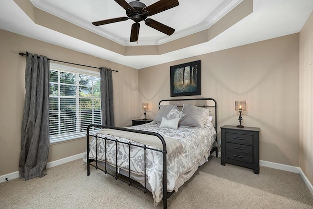 carpeted bedroom with a tray ceiling, ornamental molding, and ceiling fan