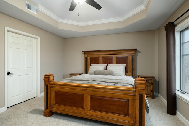 bedroom with ceiling fan, ornamental molding, a tray ceiling, and light carpet