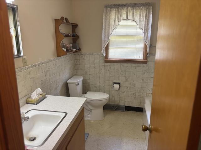 bathroom with tile walls, a healthy amount of sunlight, and a wainscoted wall