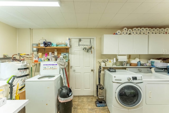 laundry room with washing machine and clothes dryer, water heater, and cabinets