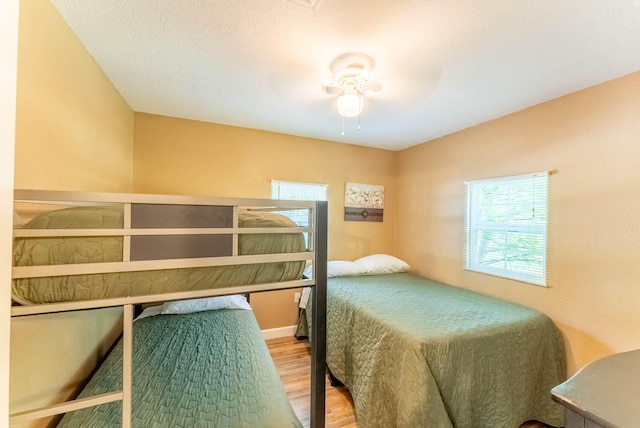 bedroom featuring ceiling fan, hardwood / wood-style floors, and multiple windows