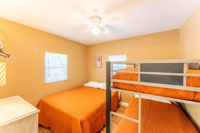 bedroom with ceiling fan, hardwood / wood-style floors, and multiple windows