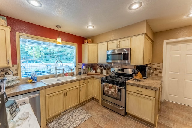 kitchen featuring light brown cabinets, decorative light fixtures, appliances with stainless steel finishes, and sink