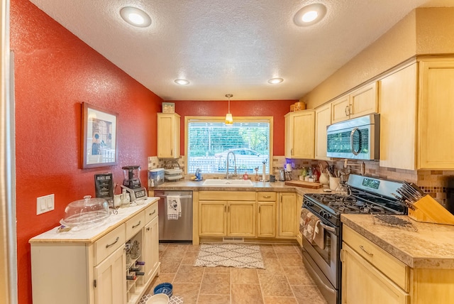 kitchen with appliances with stainless steel finishes, light brown cabinetry, decorative light fixtures, and sink