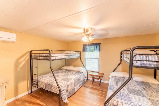 bedroom with hardwood / wood-style flooring, ceiling fan, and a wall mounted AC